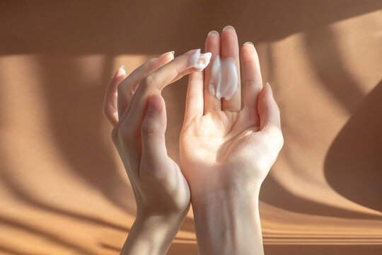 Beautiful women's palms apply cream, lotion to skin. Fingers rub white oily liquid into hands. Concept of care and beauty