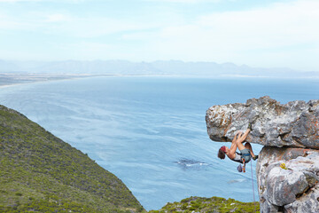 Taking thrill-seeking to new heights. A young woman climbing up the side of a mountain.