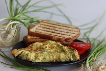 Egg omelette with finely chopped green garlic, green chillies served with butter toasted bread and fresh tomatoes