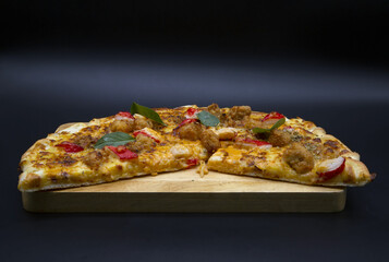 Ham and cheese pizza on a wooden tray, black background.Include Clipping Path.