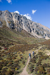 Fototapeta premium Tourists hike toward big rocky mountain in Yunnan