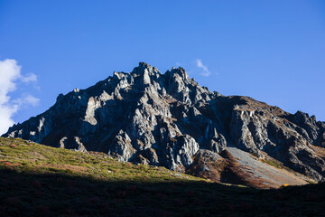 Rocky mountain peak in shadows and blue sky