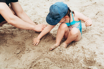 Child and parent spend time together on the beach and build a sand castle. Family vacation and parenthood concept