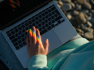 A woman is typing on a laptop. Rainbow light from a prism. 