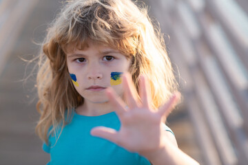 Portrait of child boy calls to Stop war in Ukraine, Stop the war hand gestures. No war, stop war, russian aggression. Human protest.