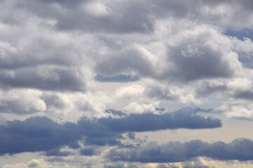Background. Sky with white cumulus horizontal clouds and gray thunderstorms. which are located below the white clouds.