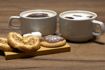 Sweet cookies, poppy seed bun and 2 mugs of coffee on the table