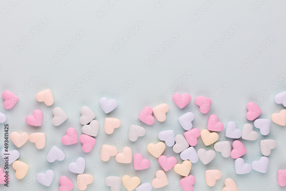 Poster Composition with candy hearts on pastel blue background.