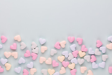 Composition with candy hearts on pastel blue background.