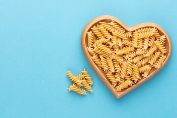 Pasta in a heart shaped wood bowl.
