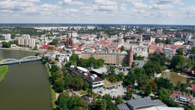 Opole, drone aerial view of Odra river, Piast bridge, Pasieka Island, Wieża Piastowska Piast Tower. Poland, late summer day. Drone real time 4k orbit backward reveal.