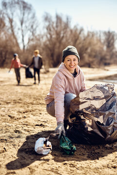 Happy Woman Doing Community Charity Work And Cleaning Beach From The Trash.