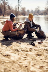 Eco aware friends cleaning trash together at lake beach.
