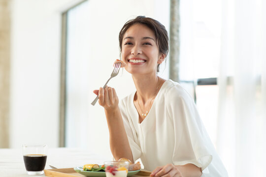 テーブルで朝食を食べようとする女性