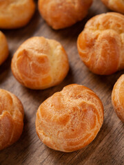 Homemade profiteroles on a wooden table. Close-up. Vertical. Selective focus. 