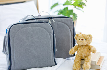 Closeup studio shot set of two gray color large multifunction multipurpose utility newborn baby toddler accessories milk bottle diaper store pocket bag with handle placed on bed with teddy bear doll