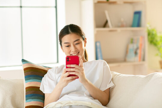 ソファーに座りスマートフォンを操作する女性