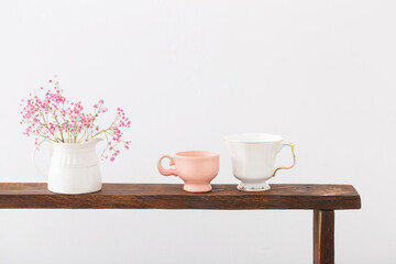 pink gypsophila and cups on  wooden shelf on  white background