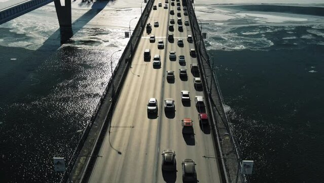 Cars move across the bridge in the background of back sunlight.