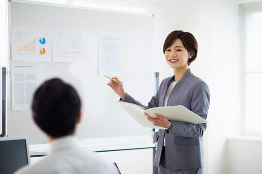 ホワイトボード前でプレゼンをする女性