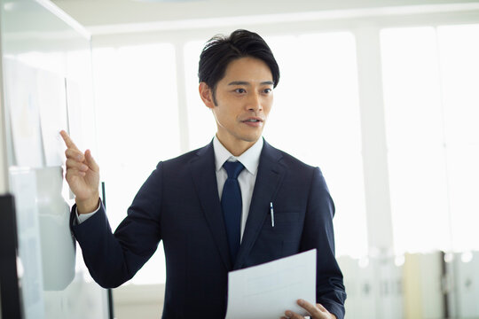 ホワイトボード前でプレゼンをする男性