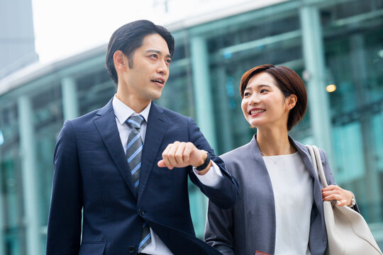 会話しながら歩くビジネススーツの男女