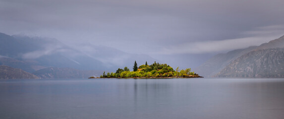 Ruby Island on Lake Wanaka with background mountains in the mist, Otago Region, South Island.
