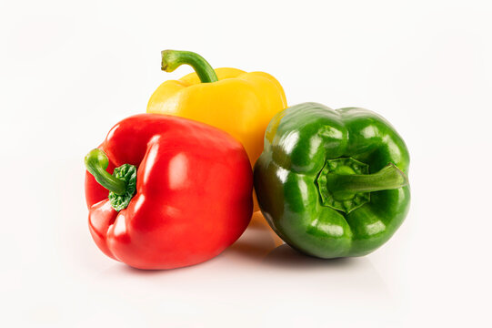 Red yellow and green bell peppers on white background