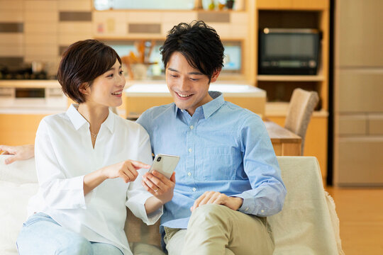 ソファーでスマートフォンを見る男女