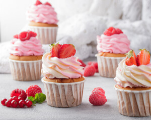 Pink cupcakes with cream and fresh berries