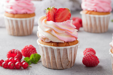 Pink cupcakes with cream and fresh berries