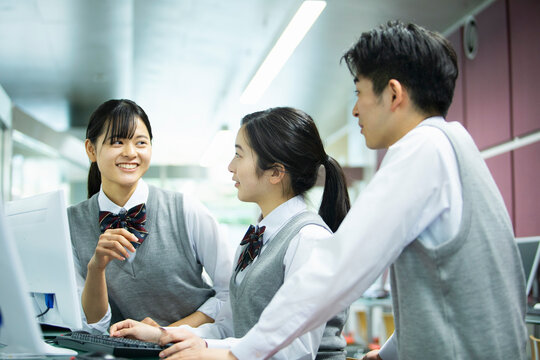 友達とパソコンを操作する女子校生