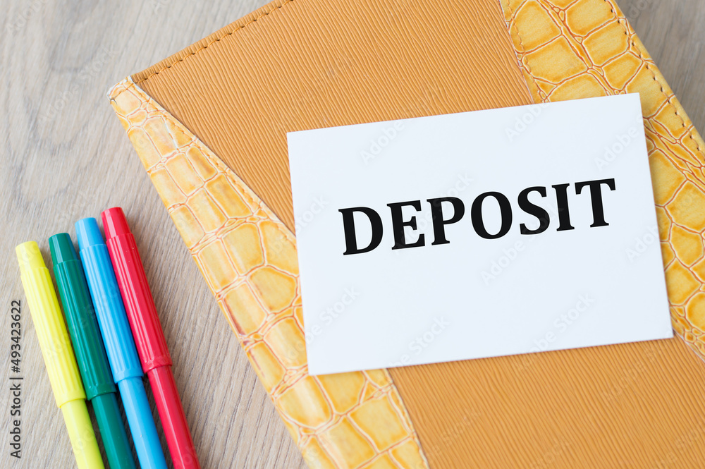 Poster deposit text on the card on the background of a yellow notebook on the table next to colored markers