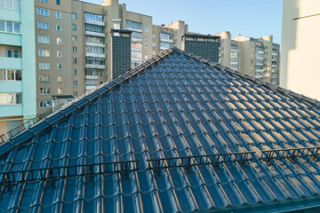 Fototapeta premium Closeup snow guard for safety in winter on house roof top covered with ceramic shingles. Tiled covering of building