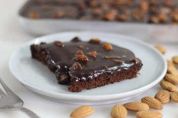 Slice of Texas sheet cake served on a plate. Buttery and chocolaty cake sliced to rectangular pieces inside the baking bin and scooped from it