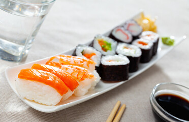 Fresh sushi maki and nigiri served on white plate with wasabi and soy sauce