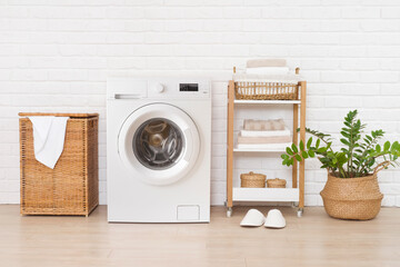 Laundry room interior with modern washing machine near brick wall