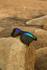 sunglasses with sand resting on a stone