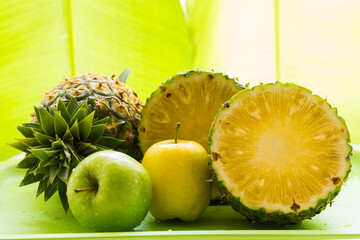 Pineapple, apple placed on a green background.