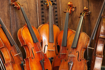 mehrere Geigen lehnen an Holzwand

