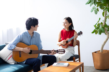 部屋で楽器を弾く男女