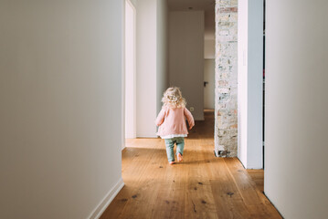 kleines blondes Mädchen läuft den Flur entlang im Haus mit Holzboden und Fußbodenheizung