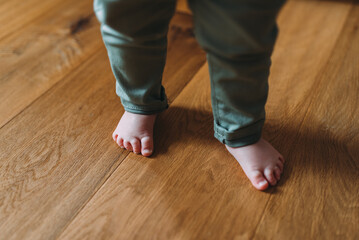 Kleines Kind barfuss mit Holz Fussboden und Heizung