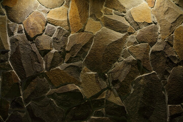 Stonework of non-formed granite stones as a background with local lighting.