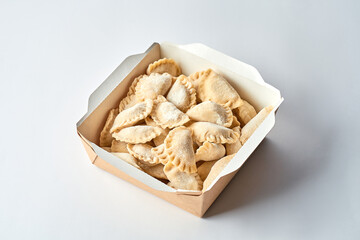 Frozen vareniki with cherries in cardboard on a gray background