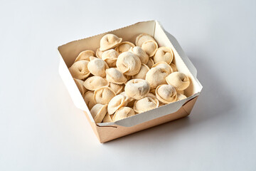 Fototapeta na wymiar Frozen dumplings in cardboard on a gray background