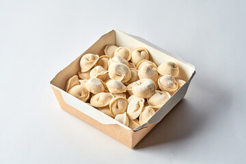 Frozen dumplings in cardboard on a gray background