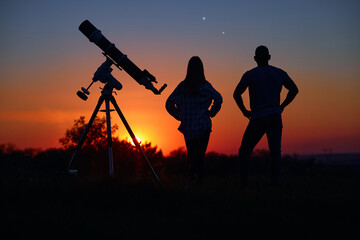 Couple stargazing together with a astronomical telescope.