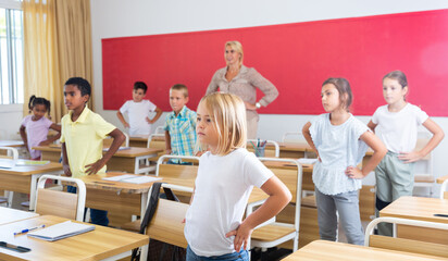 Teacher conducts gymnastics for elementary school children in the classroom