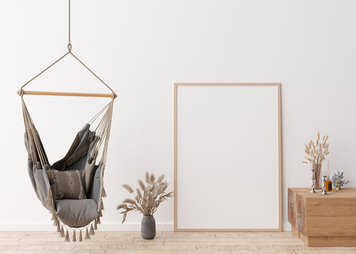 Empty vertical picture frame standing on parquet floor in modern living room. Mock up interior in scandinavian, boho style. Free space for picture. Vases with dried grass, hanging chair. 3D rendering.